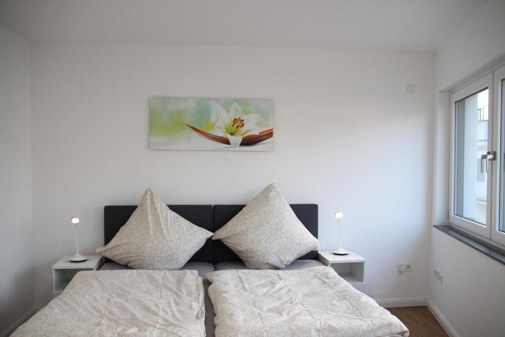 ein Bett mit Kissen und ein Gemälde an der Wand in der Unterkunft Casa Kronengarten Nr 1 in Hilden