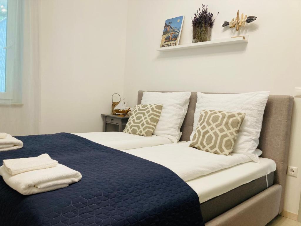 um quarto com uma cama com um cobertor azul e almofadas em ZAWIA APARTMAN em Balatonföldvár