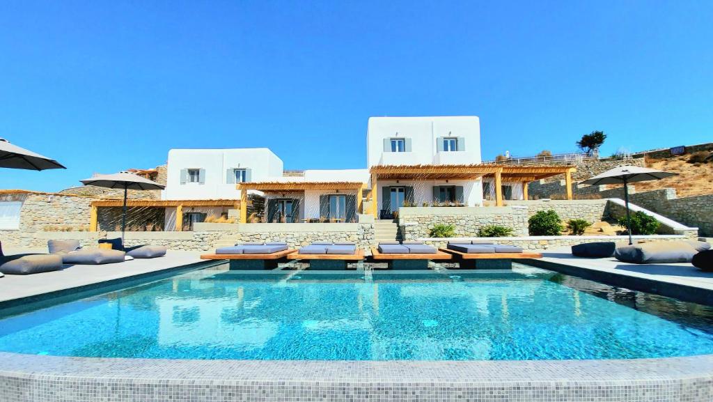 a swimming pool with chairs and a house in the background at Privilege houses Mykonos in Mýkonos City