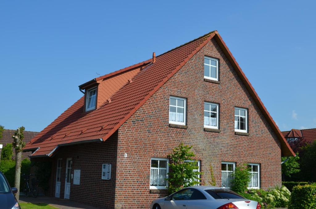 a red brick house with a gambrel roof at Ferienwohnungen Seeburger Weg in Carolinensiel