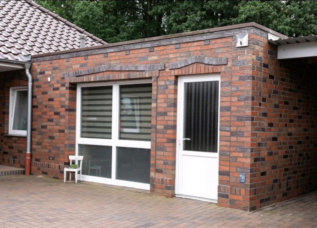 uma garagem de tijolos com uma porta branca e uma cadeira em Ferienwohnung Kleine Gasse em Lathen