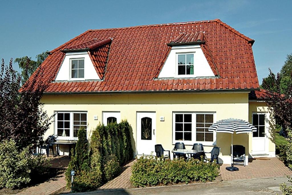 een huis met een rood dak met stoelen en een parasol bij Am Deich 49 in Zingst