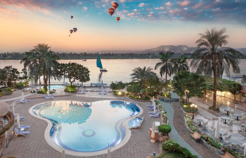 a beach filled with palm trees and palm trees at Steigenberger Nile Palace Luxor - Convention Center in Luxor