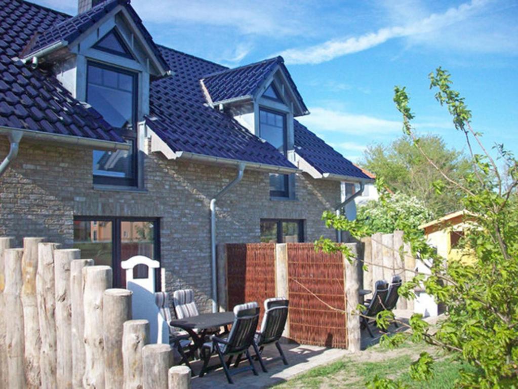 a house with chairs and a table and a fence at "Leuchtturm" in Fuhlendorf