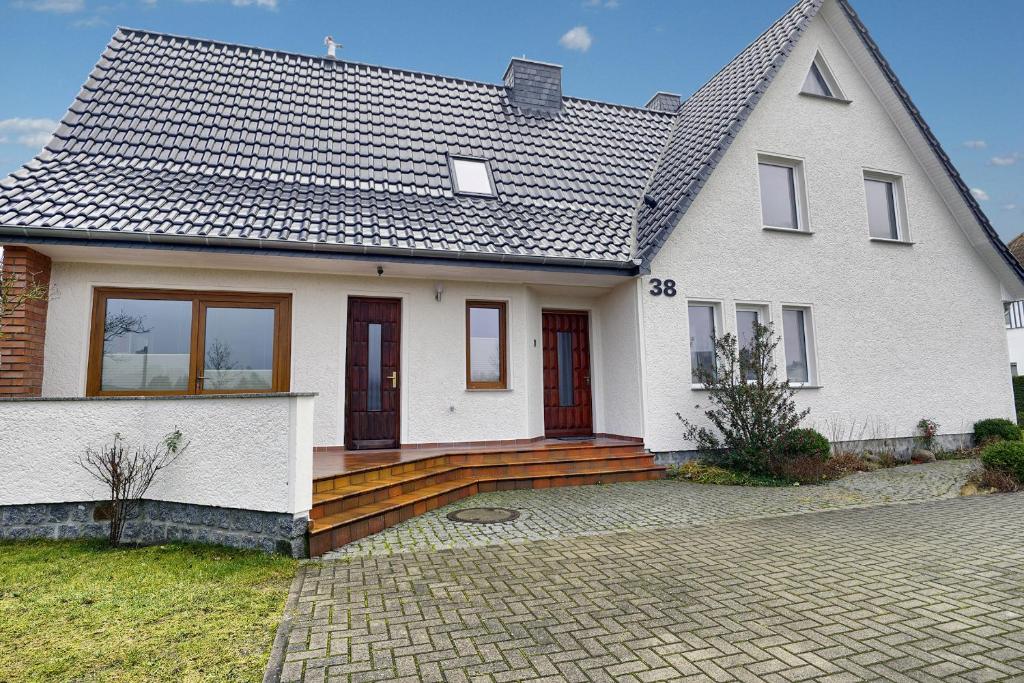 a white house with a wooden deck in front of it at Haus Havelland in Zingst