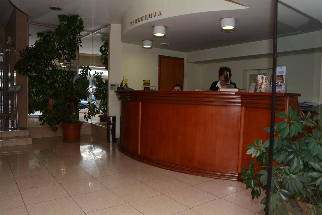 a woman sitting at a reception desk in a lobby at HOTEL OAZA in Štip