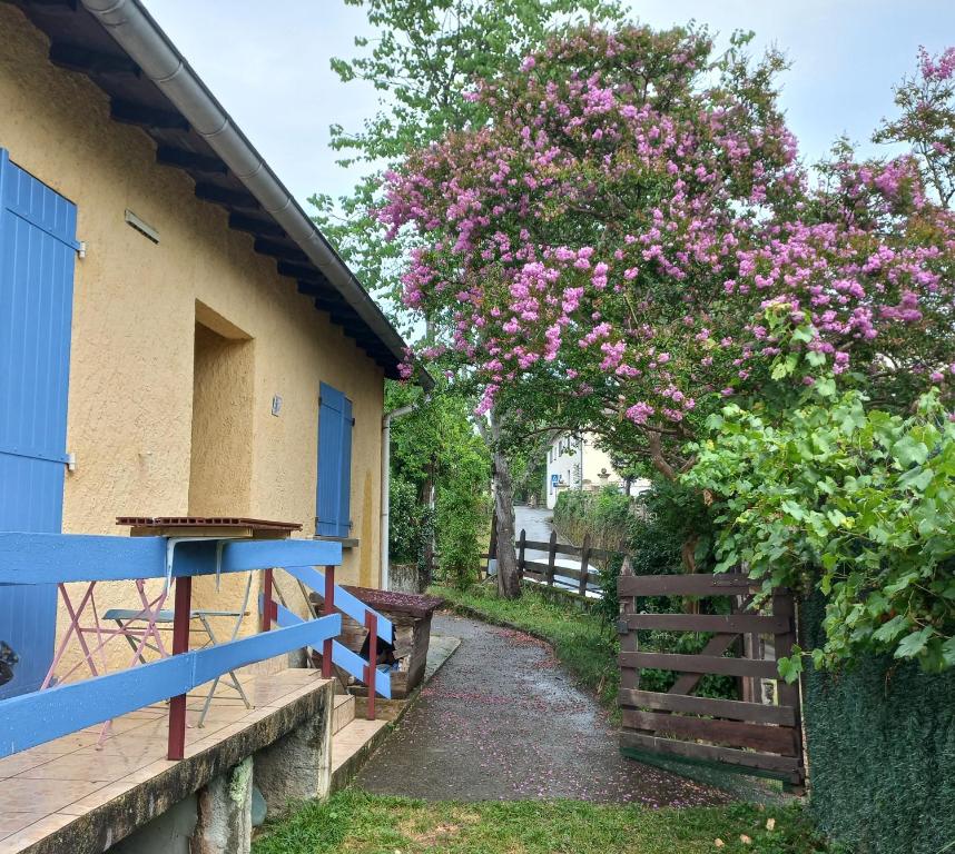 una casa con una valla azul y un árbol con flores rosas en Chambre spatieuse avec grand lit., en Aspet