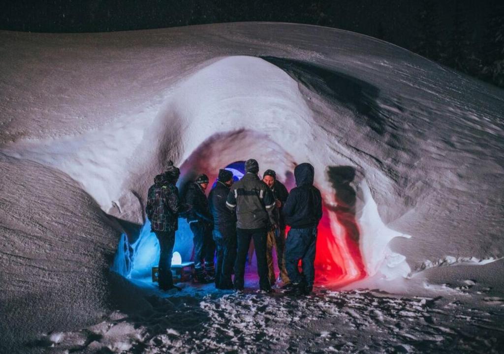 Un groupe de personnes se tenant à l'intérieur d'une grotte de glace dans l'établissement Village Igloo La Rosière, à La Rosière