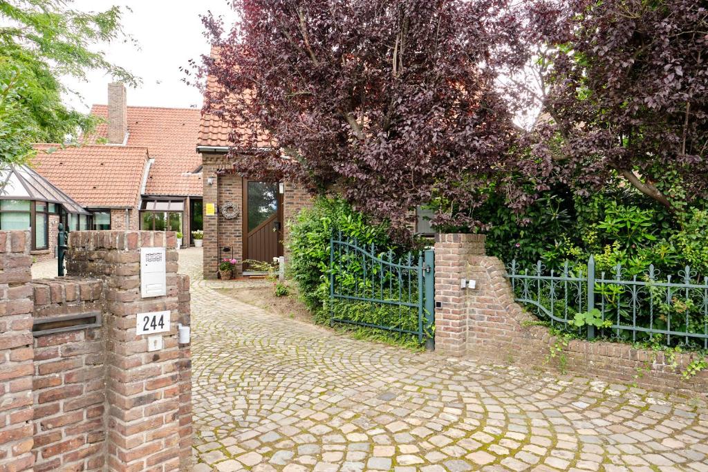 a brick fence next to a brick road with a gate at Pieters Huis in Kinrooi