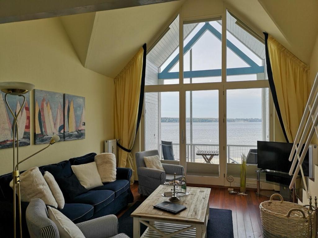 uma sala de estar com um sofá azul e uma grande janela em Soling em Laboe