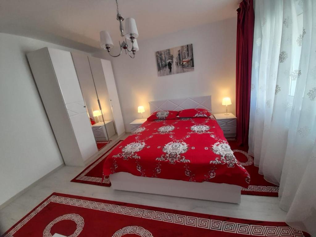 a red bed with red pillows in a white bedroom at 2 rooms apartment Telecabinei Busteni in Buşteni
