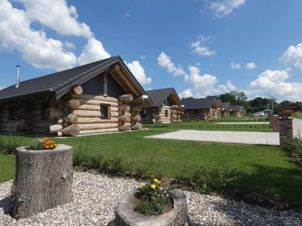 a log cabin with some flowers in front of it at Naturstammhaus Tollensesee in Krickow