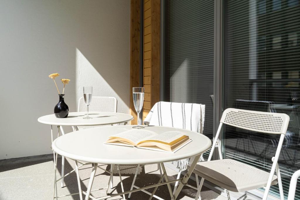 two tables and chairs with a book and wine glasses at NEW stylish 2br apartment in the city center in Oulu