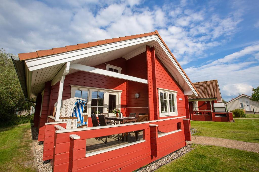 a red tiny house with a porch and a patio at Typ D "Gorch Fock" -Schärenhaus- in Pelzerhaken