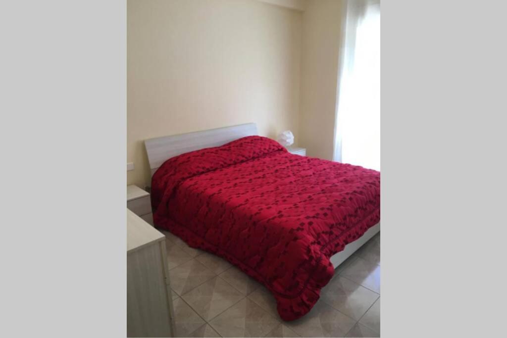 1 dormitorio con edredón rojo en la cama en Casa Helios, en Lentini