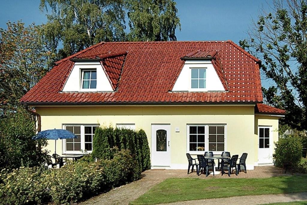 een wit huis met een rood dak en een tafel en stoelen bij Am Deich 20 in Zingst