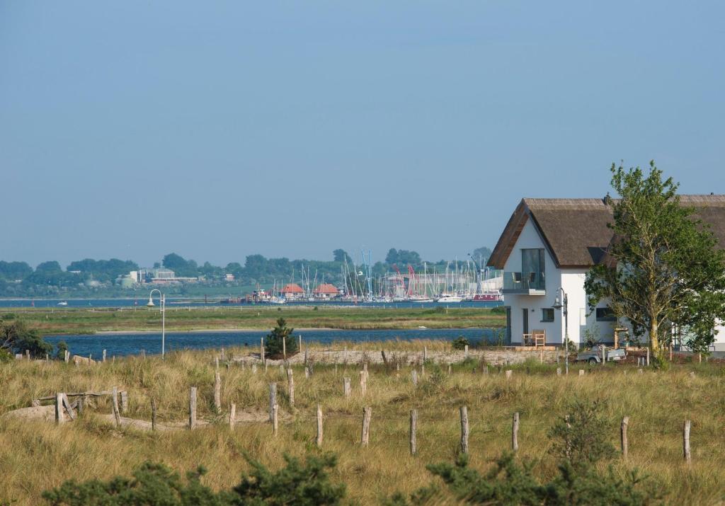 Ein weißes Haus auf einem Feld mit einem Zaun in der Unterkunft Ostsee - Reetdachhaus Nr 40 "Utkiek" im Strand Resort in Heiligenhafen