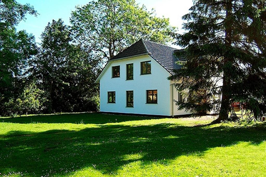 a white house on a green field with trees at Hütigendachs, FW 4 in Zingst
