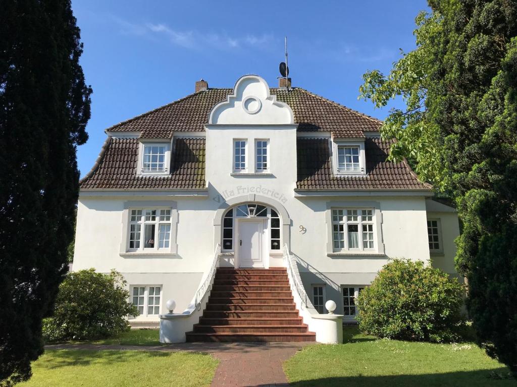 una gran casa blanca con escaleras que conducen a ella en Villa Friedericia - Whg1, en Wyk auf Föhr