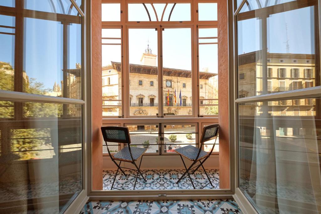 2 Stühle auf einem Balkon mit Blick auf ein Gebäude in der Unterkunft Hotel Cappuccino - Palma in Palma de Mallorca