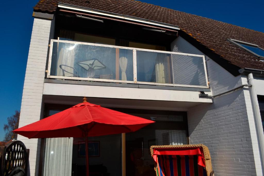 een rode paraplu en twee stoelen voor een huis bij Cantay-Mathildenstraße 16 - FW 4 - OG rechts in Fehmarn