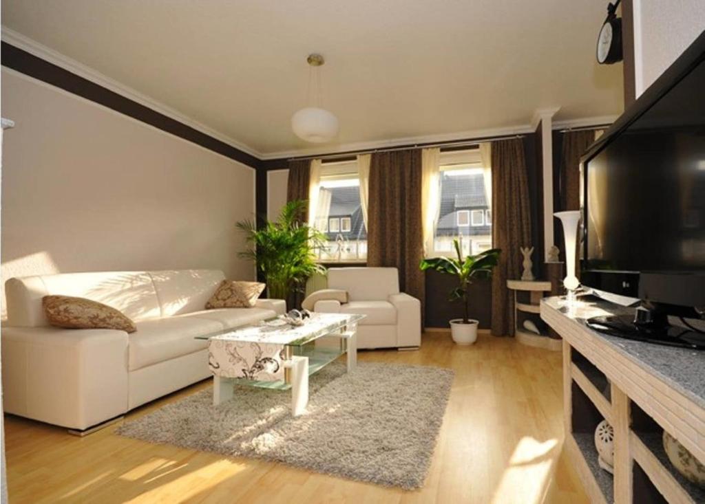 Deluxe Apartments Bremen Typ C في بريمين: غرفة معيشة مع أريكة بيضاء وتلفزيون