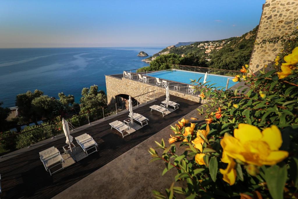 Blick auf einen Pool mit Stühlen und das Meer in der Unterkunft Dominio Mare Resort & SPA in Bergeggi