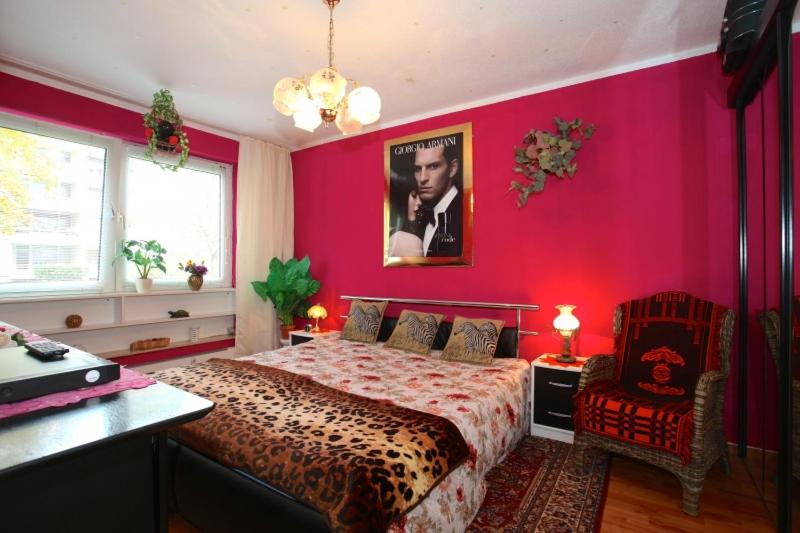 a bedroom with a red wall with a bed and a chair at Private Rooms in Hannover