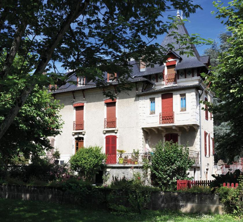 duży biały dom z czerwonymi drzwiami i oknami w obiekcie Le Béarn sous les toits w mieście Nay