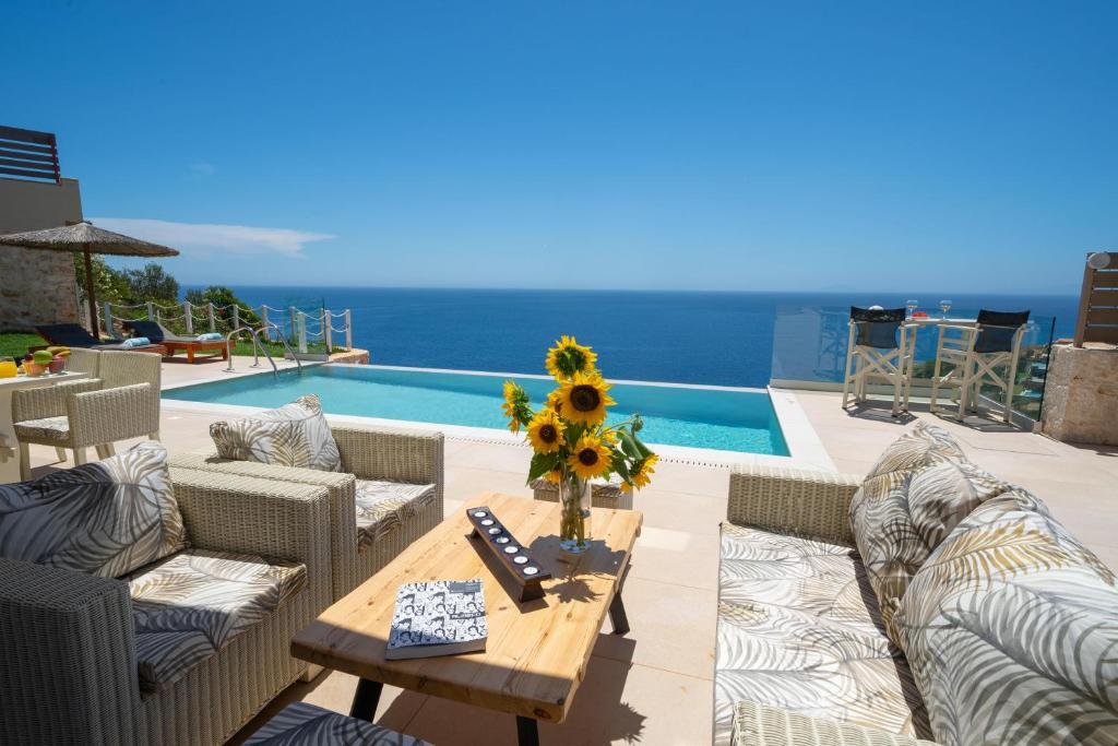 eine Terrasse mit Sofas und einem Tisch mit Sonnenblumen in der Unterkunft Tsimaras Villas in Skala