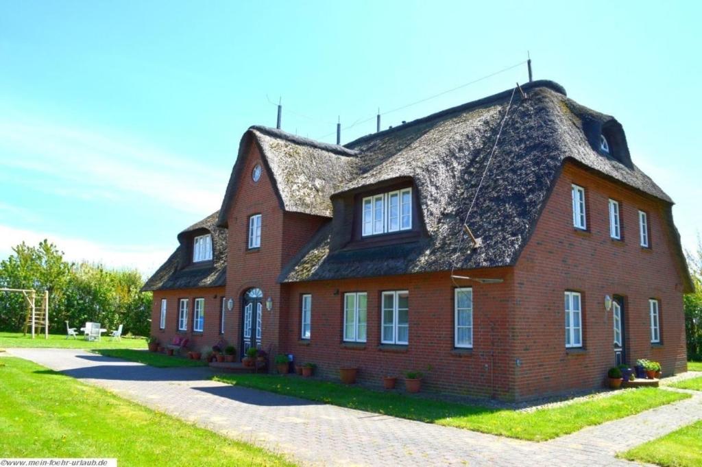 un grand bâtiment en briques rouges avec un toit de chaume dans l'établissement Luv - a05408, à Dunsum