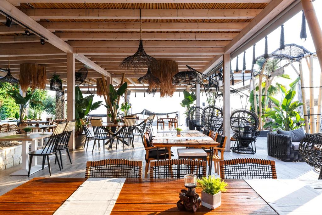 restauracja z drewnianymi stołami i krzesłami oraz stolarką w obiekcie Blue Carpet Luxury Suites w mieście Pefkochori
