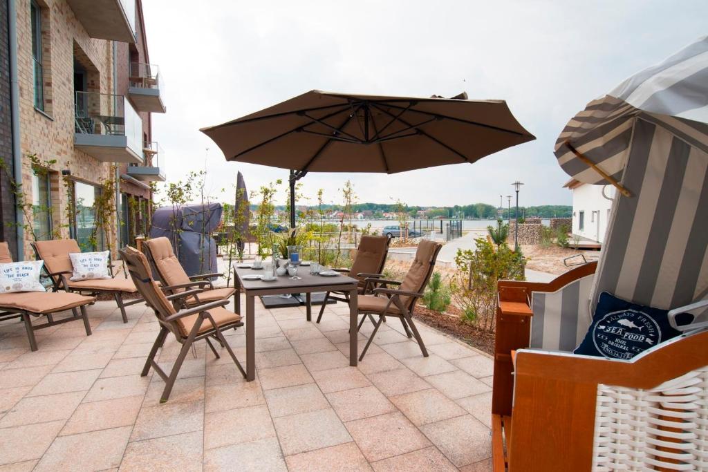 a patio with a table and chairs and an umbrella at Ostsee - Appartement Nr 171 "Dünengras" im Strand Resort in Heiligenhafen