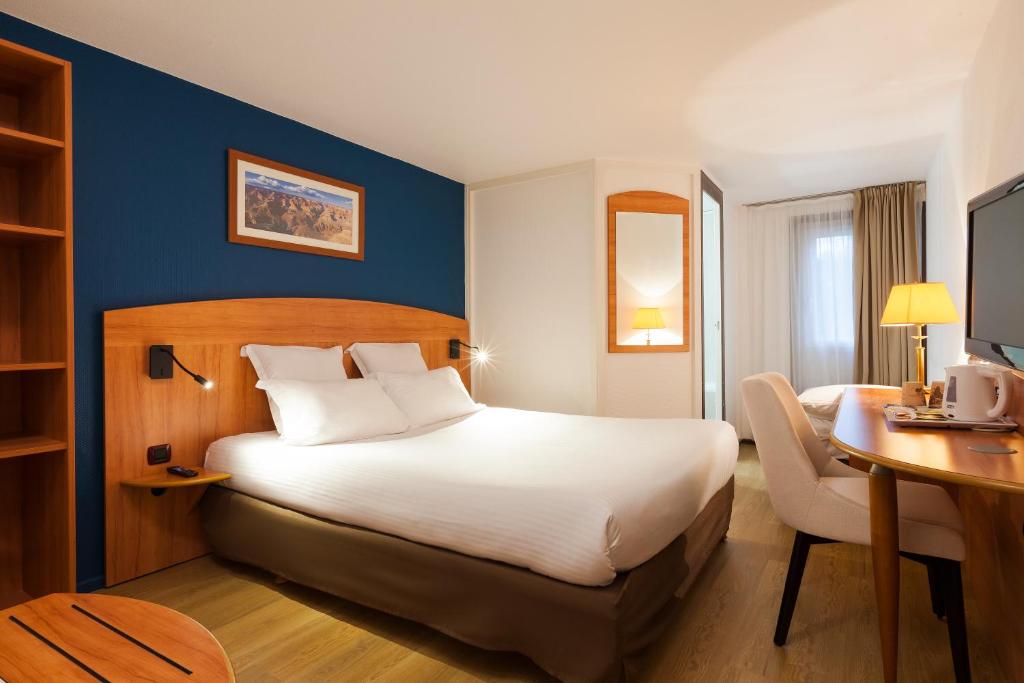Habitación de hotel con cama grande y escritorio. en Comfort Hotel Evreux en Évreux