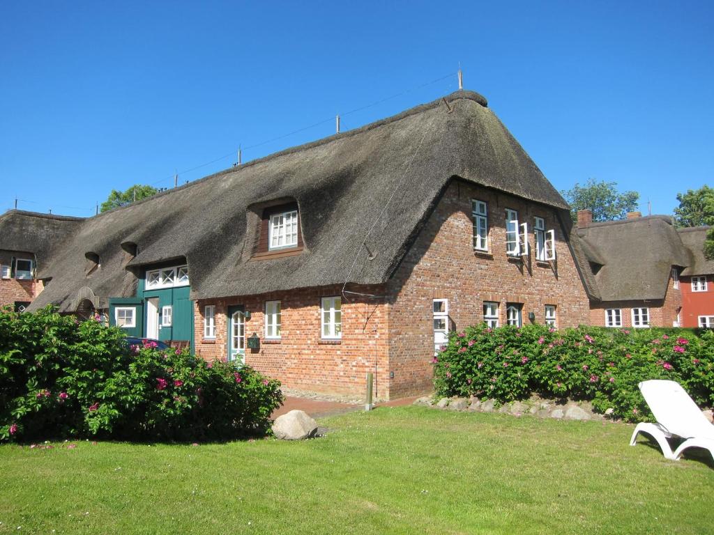 a large brick house with a thatched roof at Nordseekrabbe 12 Herrenhof in Wrixum