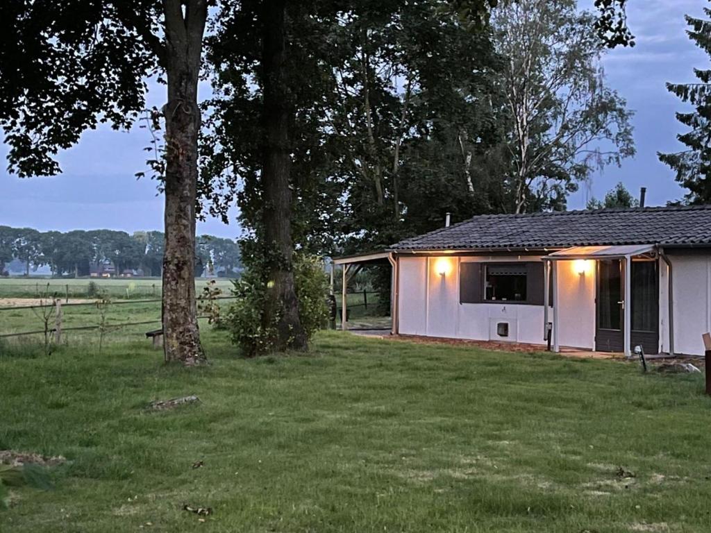 um barracão branco com luzes ao lado de um campo em De Bargsche Hoeve em Azewijn