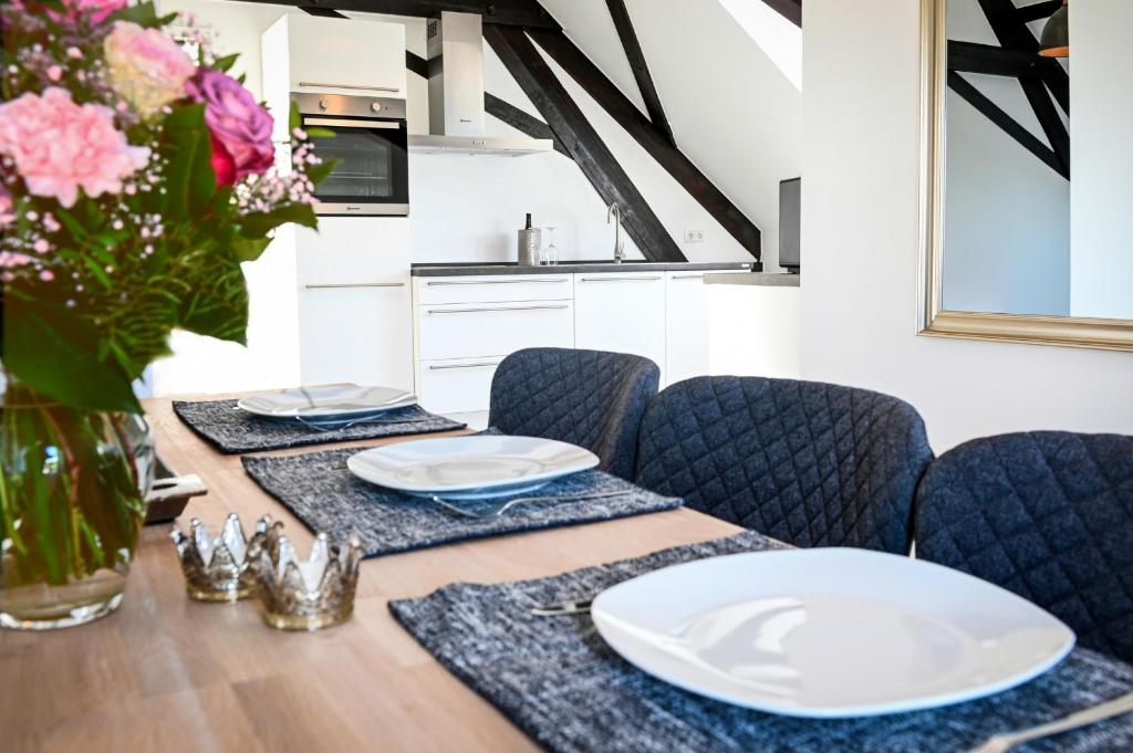 ein Esszimmer mit einem Tisch mit Tellern und Stühlen in der Unterkunft Seen-Apartment im Herrenhaus Rheinblick in Xanten