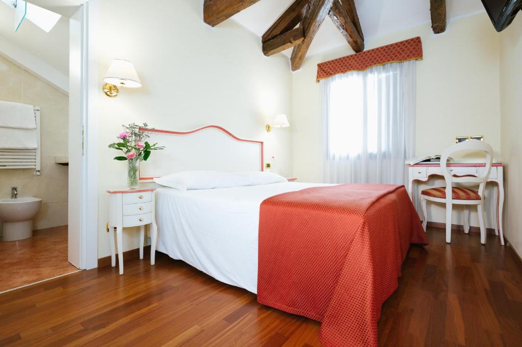a bedroom with a white bed with a red blanket at Hotel Do Pozzi in Venice