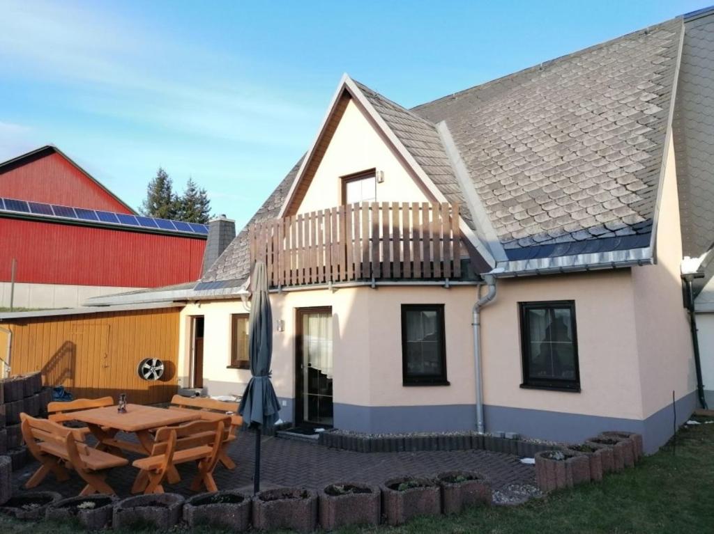 uma casa com um deque de madeira e uma mesa em Ferienhaus Ostwald em Deutscheinsiedel