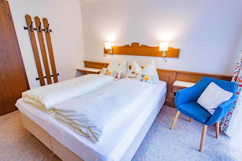 ein Schlafzimmer mit einem Bett und einem blauen Stuhl in der Unterkunft Soldanella 6 by Alpenidyll Apartments in Ramsau am Dachstein