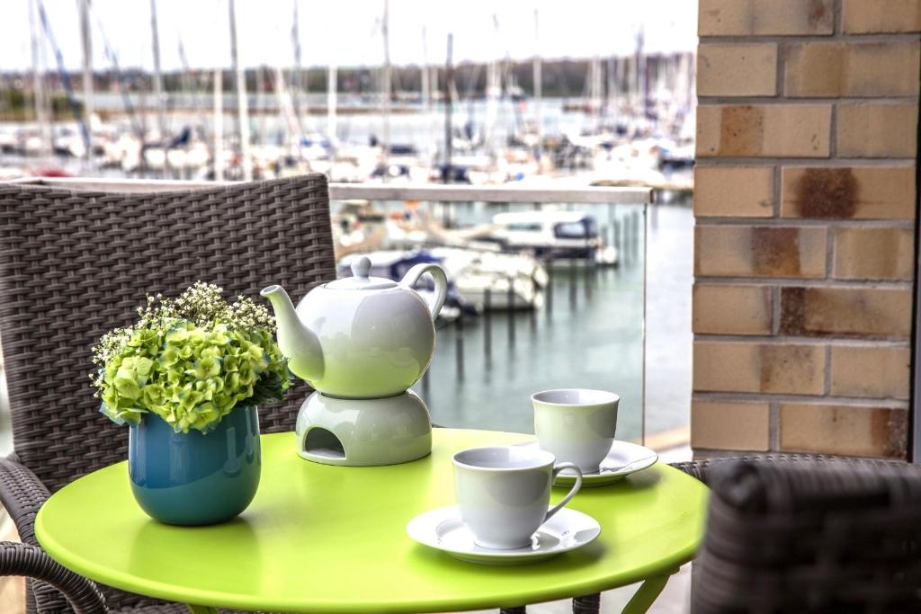 a table with two cups and a tea pot and flowers on it at Ostsee - Appartement "Pier 77" im Strand Resort in Heiligenhafen