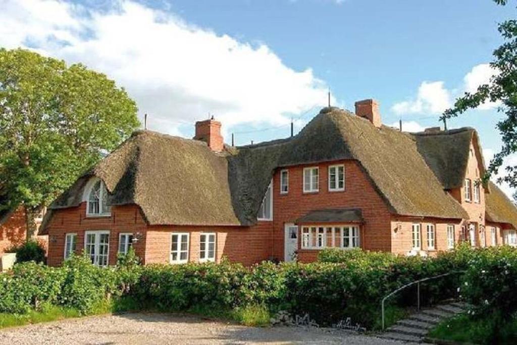 a large red brick house with a roof at Pastoratshof Whg 4 in Wrixum