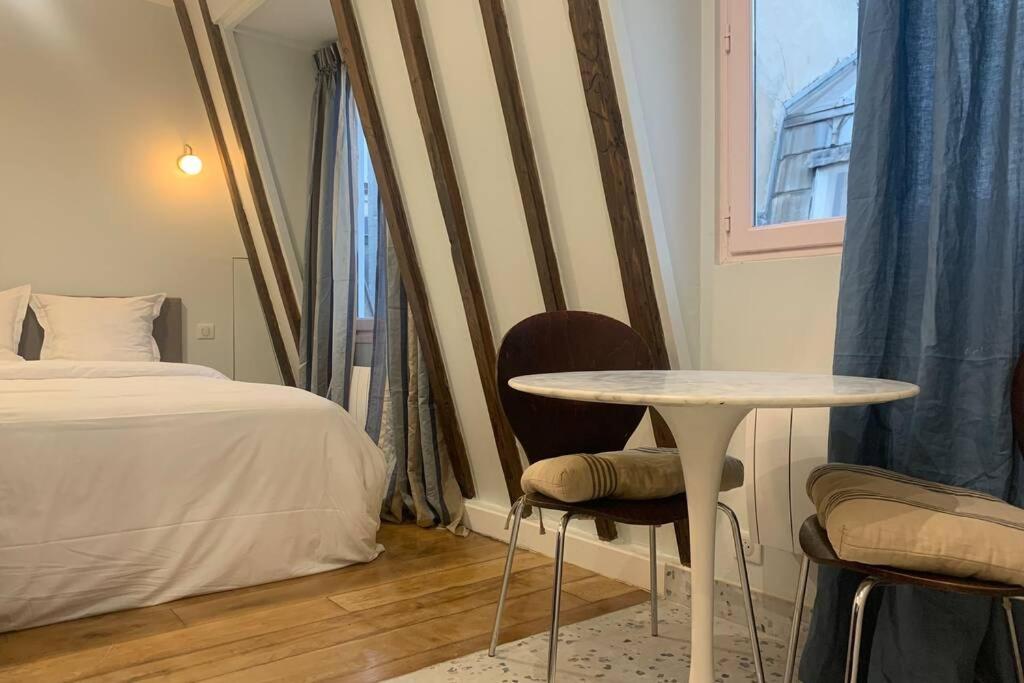 une chambre avec un lit, une table et des chaises dans l'établissement PARIS 4 LE MARAIS Hôtel de Ville LIFT, à Paris