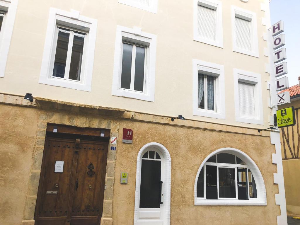 um edifício com uma porta de madeira e janelas em Logis Hôtel Restaurant Métropole em Mirande