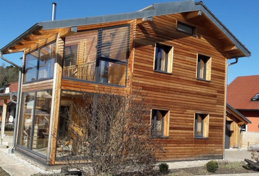 ein Holzhaus mit vielen Fenstern in der Unterkunft Naturhaus Altmuehltal in Emsing