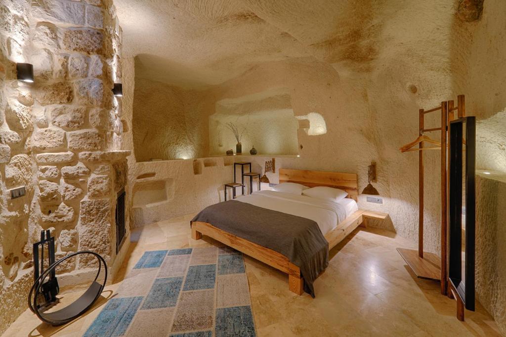 a bedroom with a bed and a stone wall at Luvi Cave Hotel in Göreme