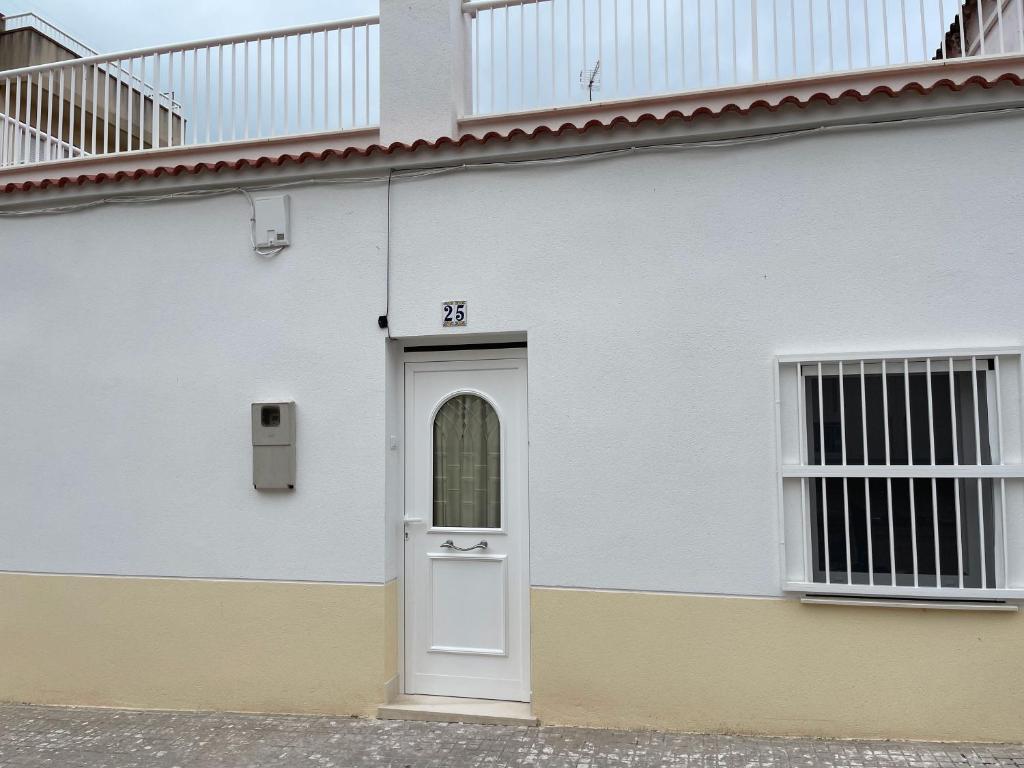a white building with a white door on it at Lleida 25, casa a planta baixa amb àmplia terrassa equipada amb barbacoa in Sant Carles de la Ràpita