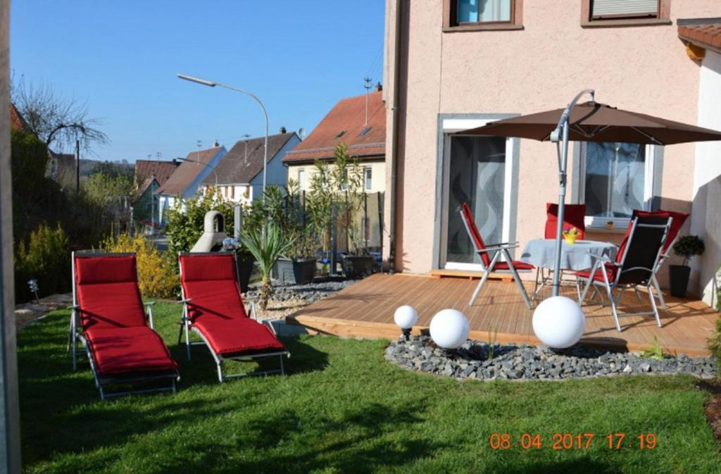 un grupo de sillas y un paraguas en un patio en Ferienwohnung Anita, en Rulfingen