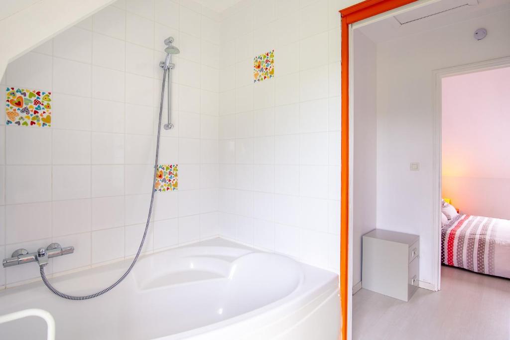 a white bathroom with a tub and a shower at Le Galop in Tréméreuc