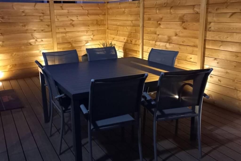 una mesa y sillas en una habitación con paredes de madera en Gîte le C-47, en Sainte-Mère-Église